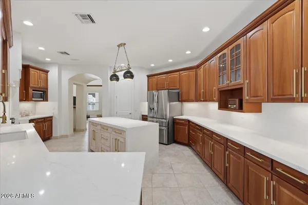 a large kitchen with stainless steel appliances a large counter top a stove a sink dishwasher a refrigerator and cabinets