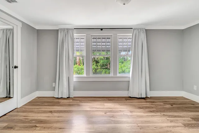 a view of an empty room with wooden floor and a window