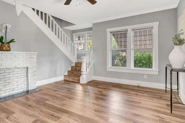 a view of an empty room with wooden floor and a window