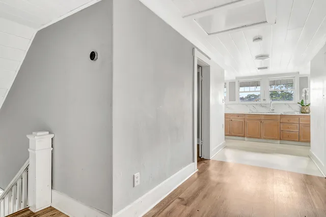 a view of a hallway with wooden floor and a kitchen