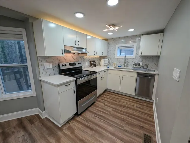 a kitchen with stainless steel appliances granite countertop a stove top oven a sink and a refrigerator