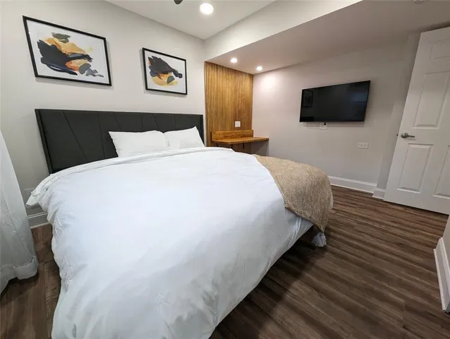 a large bed sitting in a bedroom and a flat tv screen on dresser