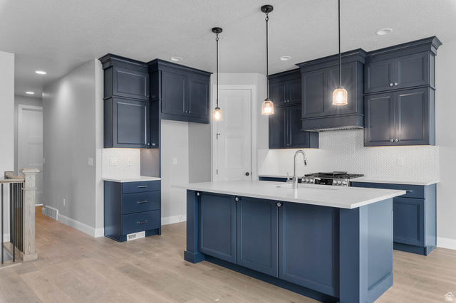 11673 South Halls Crk Road Draper, UT 84020 - Photo 11 of 22 Contemporary kitchen featuring navy blue cabinetry, white countertops, a white hexagonal tile backsplash, stainless steel appliances, and pendant lighting