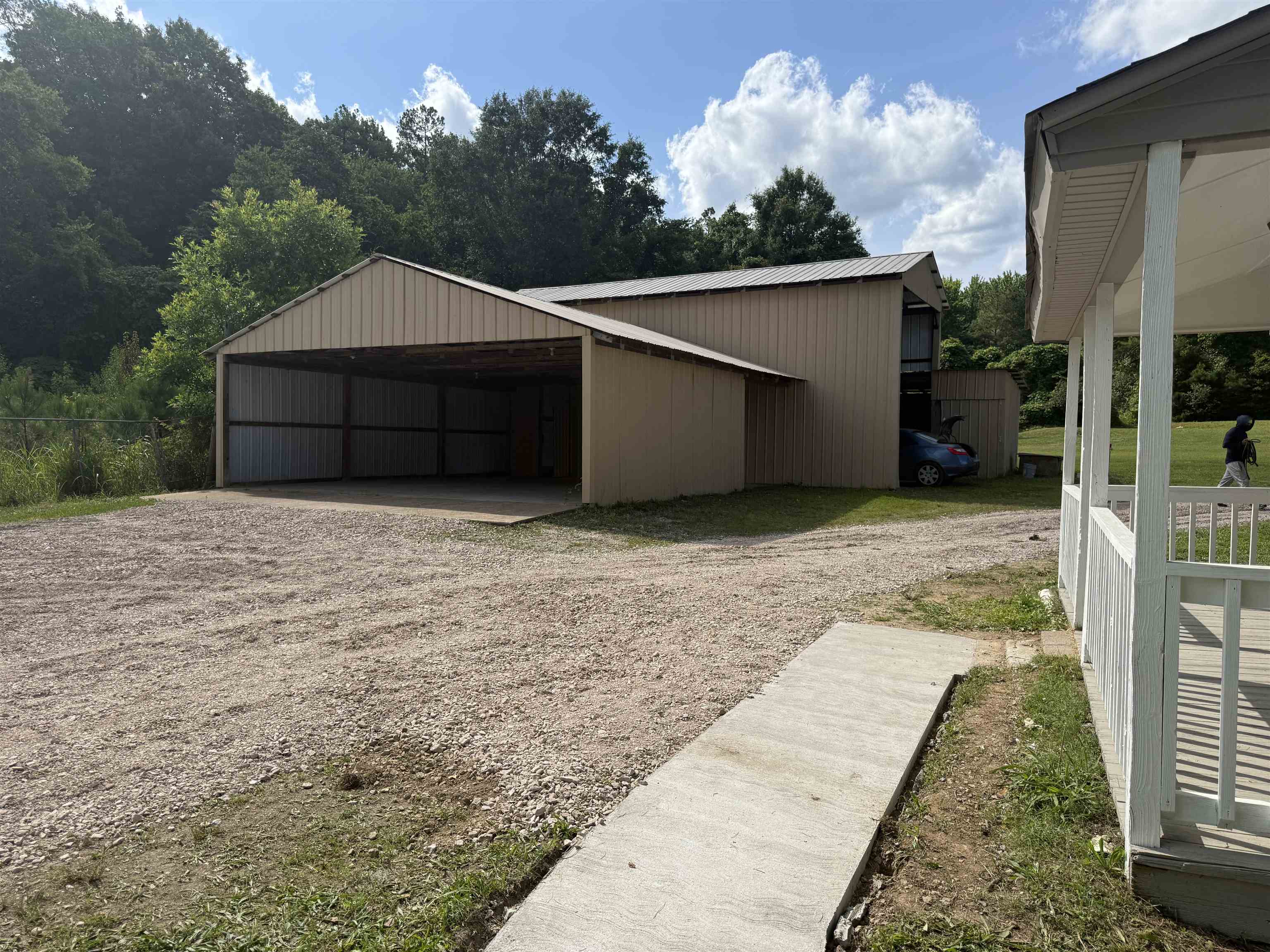 170 Leapwood Road Enville, TN 38332 - Photo 6 of 33 Expansive gravel driveway leading to a large metal outbuilding with a two-bay carport, offering significant covered storage