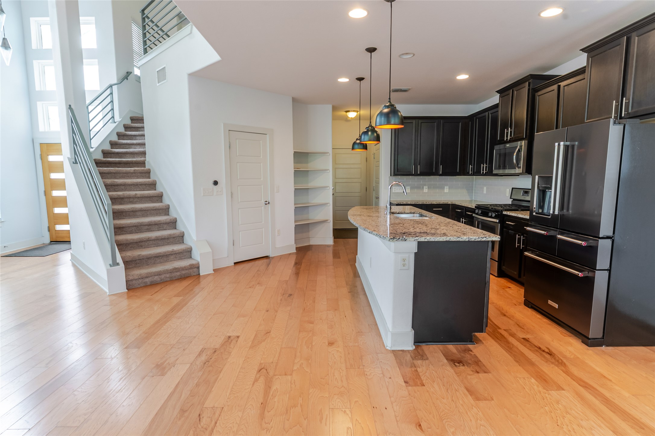 1400 Homespun Road Austin, TX 78745 - Photo 7 of 30 Gleaming hardwood floors and a central prep island anchor this functional kitchen layout.