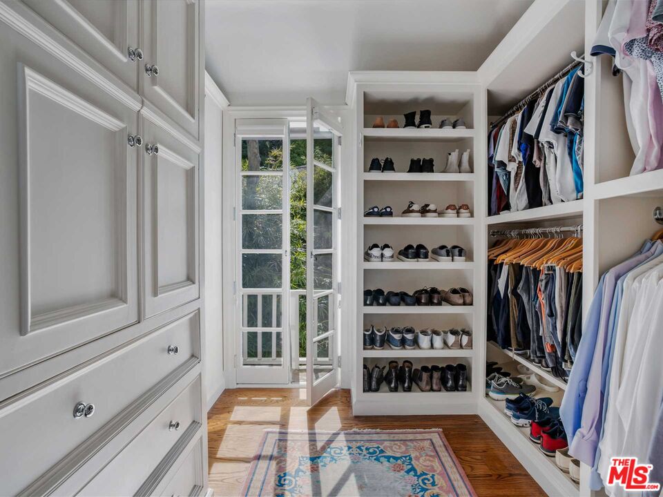 a view of walk in closet with clothes and shoes