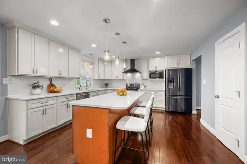 a large open kitchen with a refrigerator a stove a sink and a dining table with wooden floor