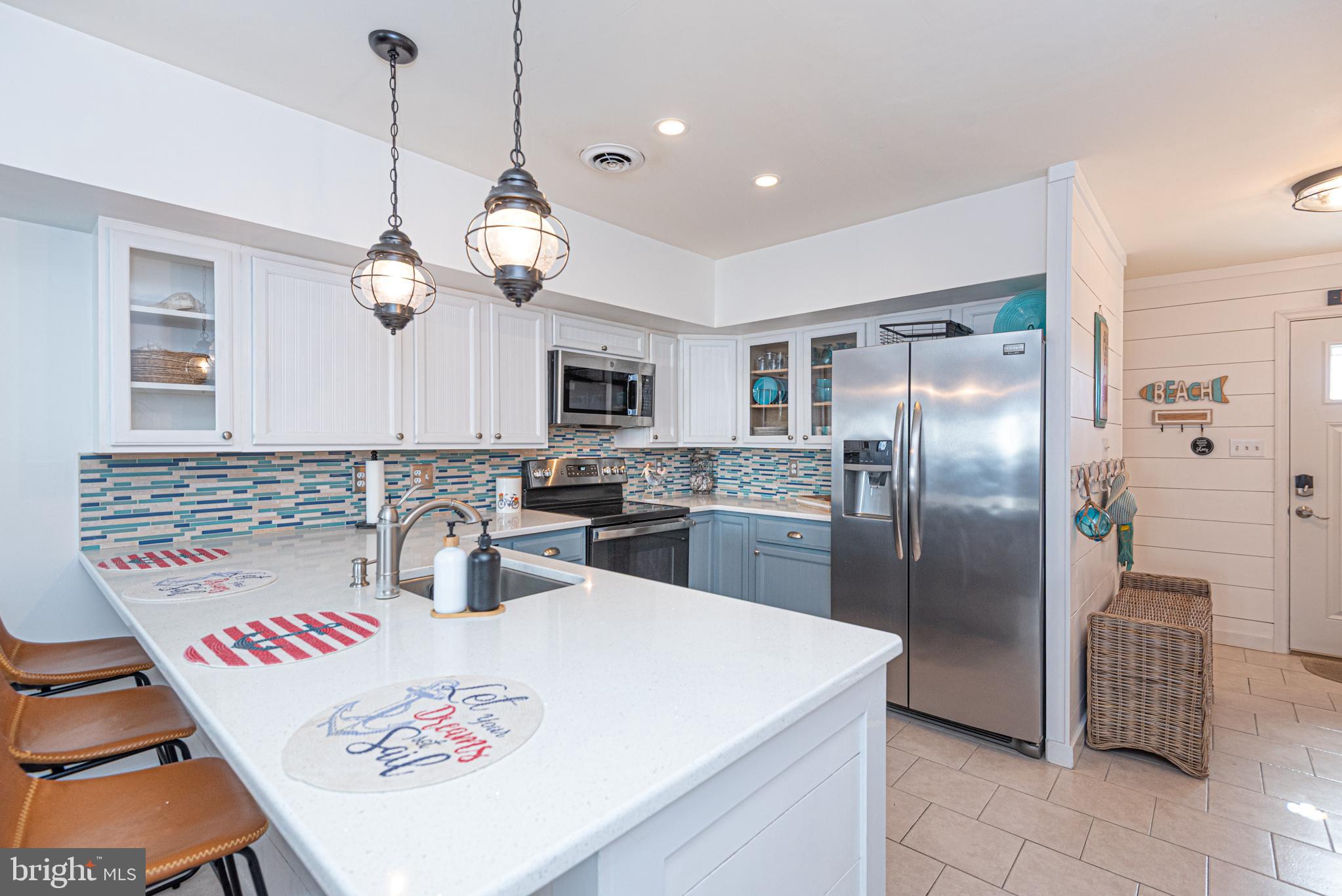 702 Bradley Road, Unit 11 Ocean City, MD 21842 - Photo 25 of 92 a kitchen with stainless steel appliances granite countertop a sink a stove a refrigerator cabinets a dining table and chairs