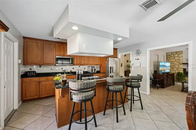 a kitchen with stainless steel appliances kitchen island granite countertop a table chairs sink and cabinets