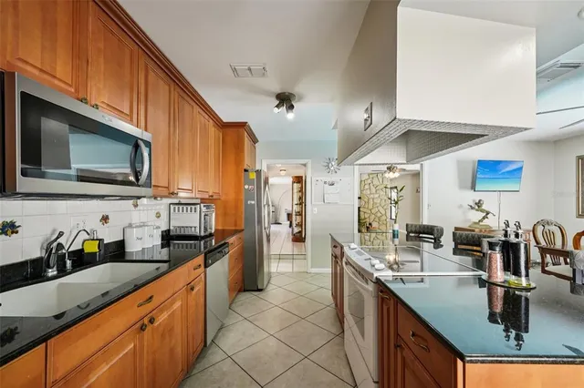 a kitchen with stainless steel appliances granite countertop a sink a stove top oven a counter space and cabinets