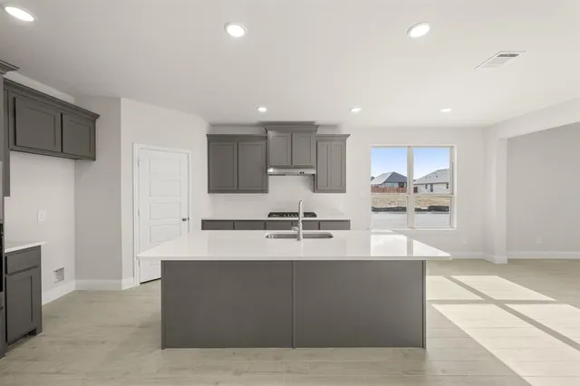 a large kitchen with kitchen island a sink a stove a refrigerator and a cabinets