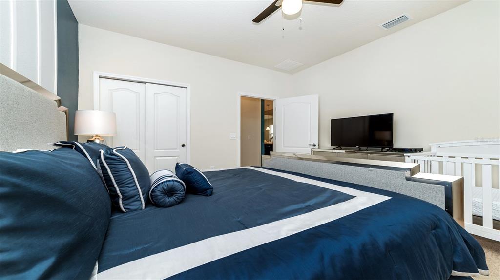 8894 Qin Loop Davenport, FL 33896 - Photo 16 of 47 a bedroom with a bed and a flat screen tv