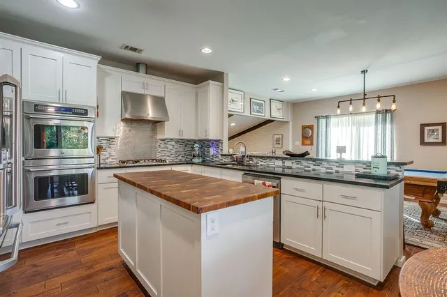 a kitchen with stainless steel appliances granite countertop a stove a sink and a microwave