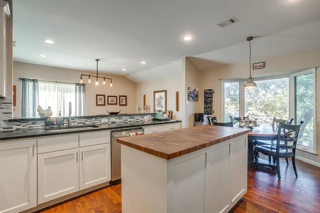 a kitchen with granite countertop white cabinets and wooden floors