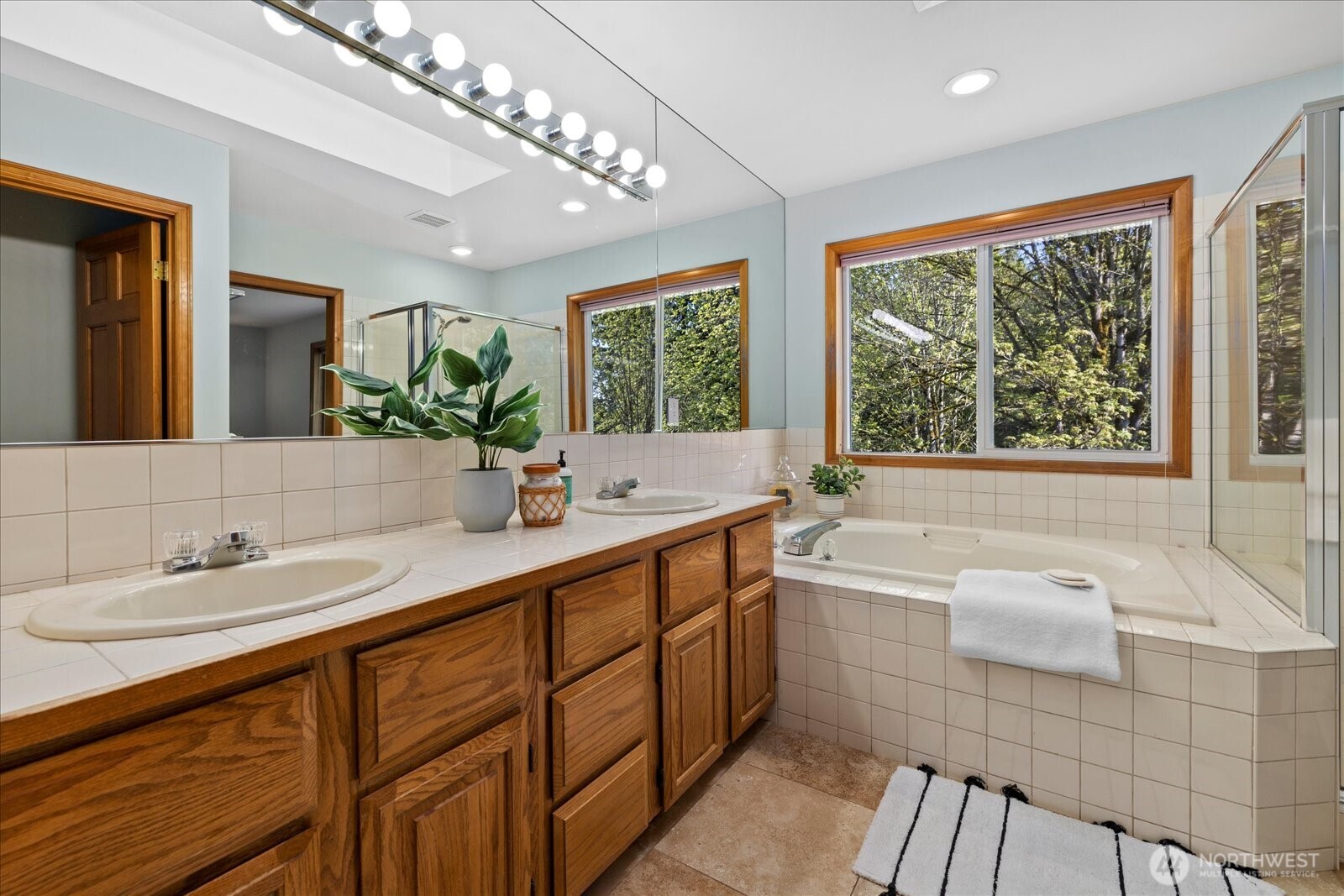 10906 Northeast 197th Street Bothell, WA 98011 - Photo 24 of 38 a bathroom with a double vanity sink a large mirror and a bathtub