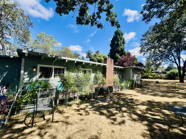 a backyard of a house with table and chairs under an umbrella
