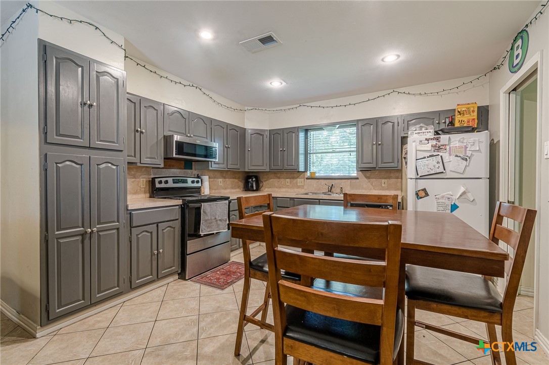 133 Algarita Road San Marcos, TX 78666 - Photo 21 of 43 a kitchen with stainless steel appliances a stove a refrigerator cabinets and a dining table
