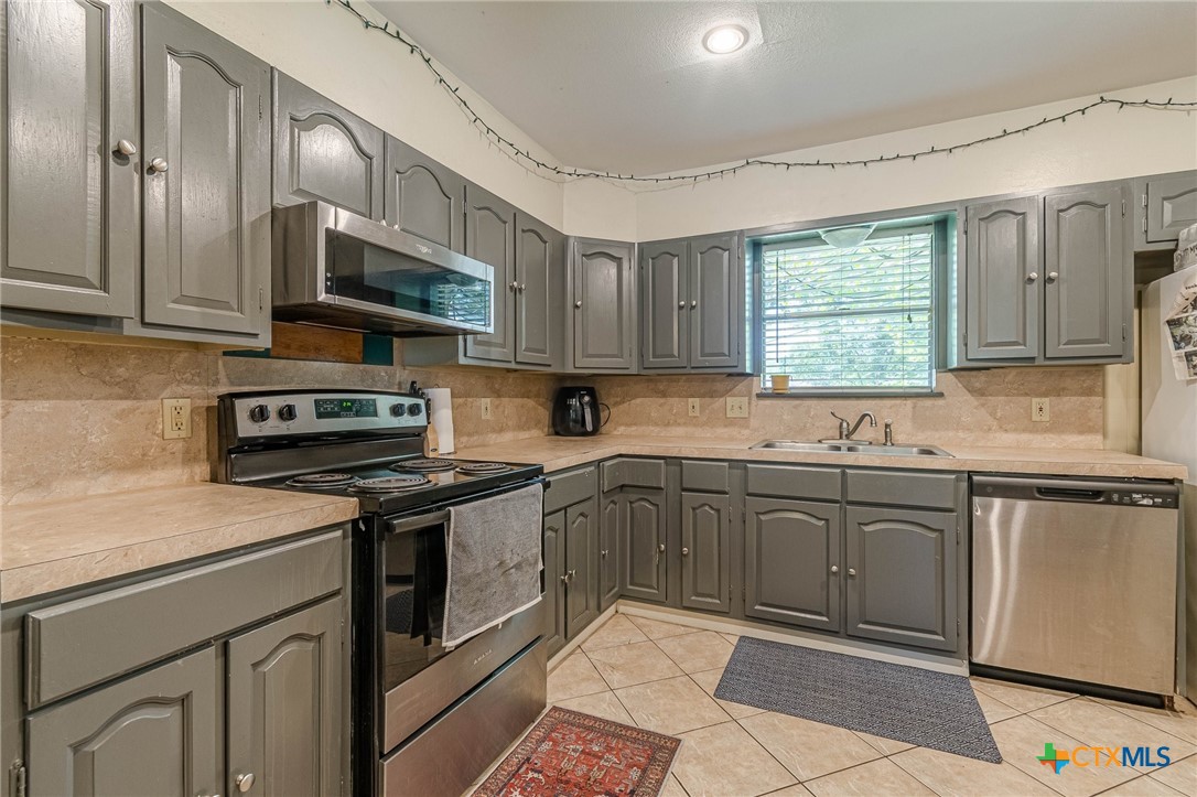133 Algarita Road San Marcos, TX 78666 - Photo 22 of 43 a kitchen with stainless steel appliances granite countertop a stove sink microwave and window