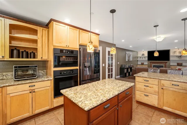 a kitchen with stainless steel appliances kitchen island granite countertop a stove top oven a sink dishwasher a dining table and chairs with wooden floor