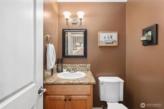 a bathroom with a granite countertop sink a toilet and mirror