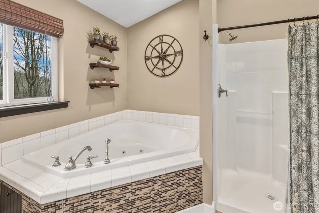 a bathroom with a bathtub a shower and a window