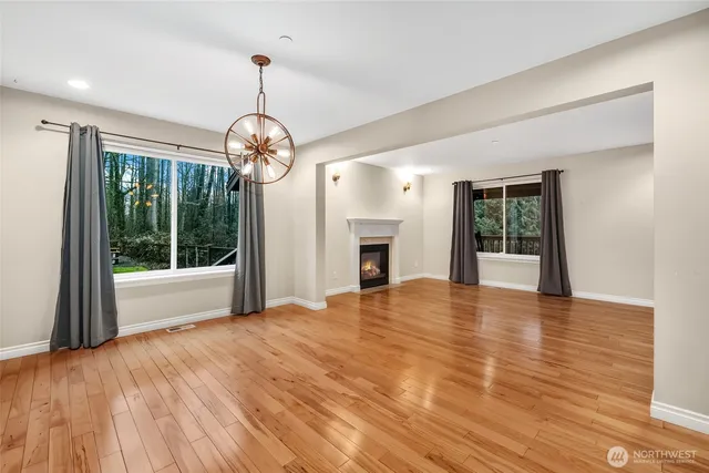 a view of an empty room with wooden floor fireplace and a window