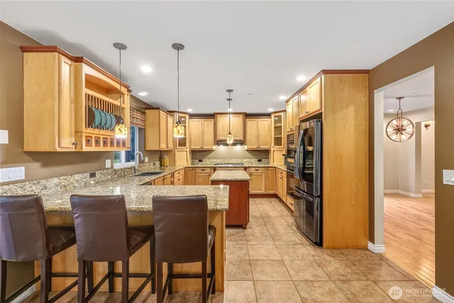 a kitchen with stainless steel appliances granite countertop a refrigerator a stove a sink and chairs