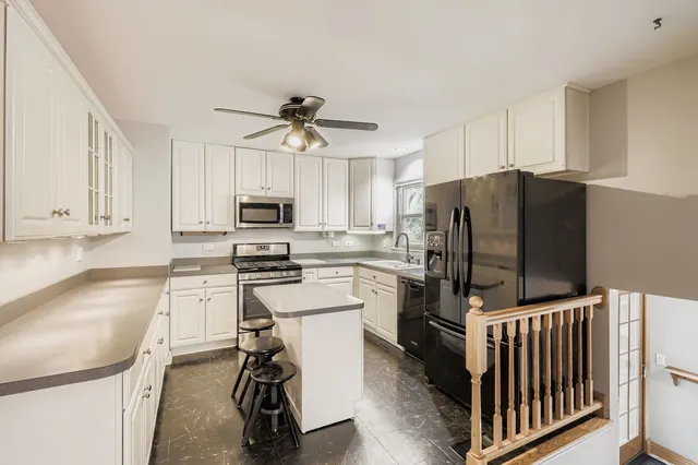 a kitchen with stainless steel appliances a refrigerator a stove a sink and white cabinets