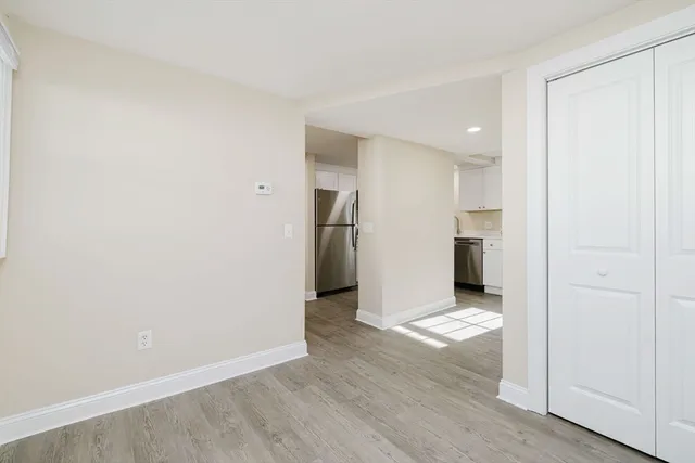 an empty room with closet and a kitchen