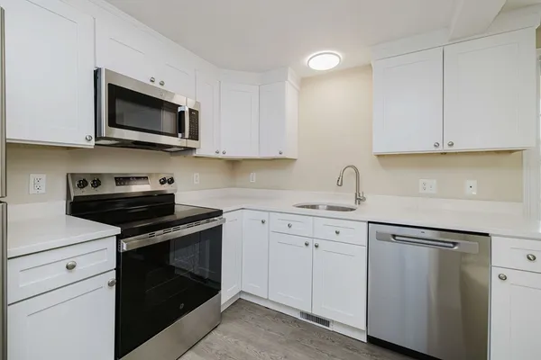 a kitchen with white cabinets and stainless steel appliances