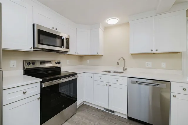 a kitchen with white cabinets and stainless steel appliances