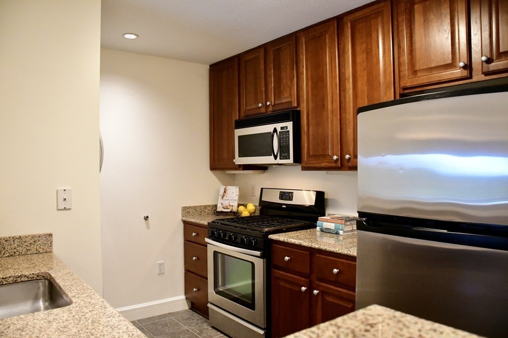 36 Village Road, Unit 713 Middleton, MA 01949 - Photo 10 of 39 a kitchen with stainless steel appliances granite countertop a stove a sink and a microwave