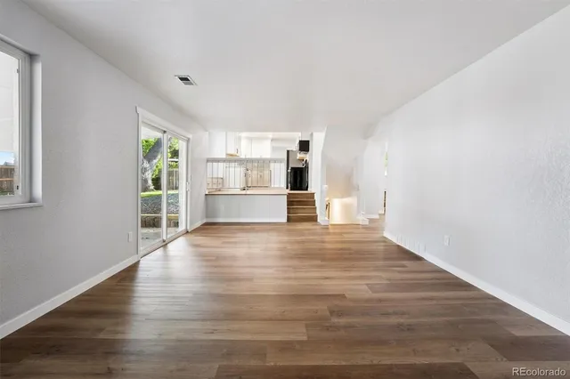 a view of empty room with wooden floor and windows