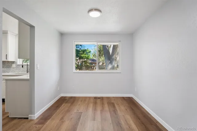 an empty room with a window and wooden floor
