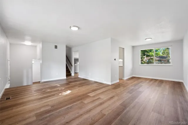 a view of empty room with wooden floor and window