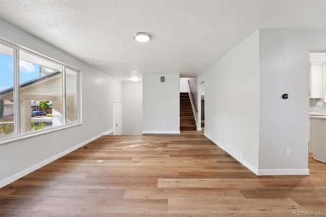 a view of an empty room with wooden floor and a window