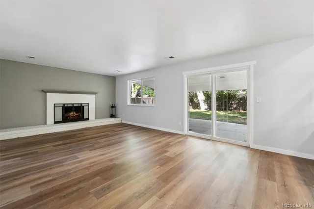 a view of empty room with wooden floor and fireplace