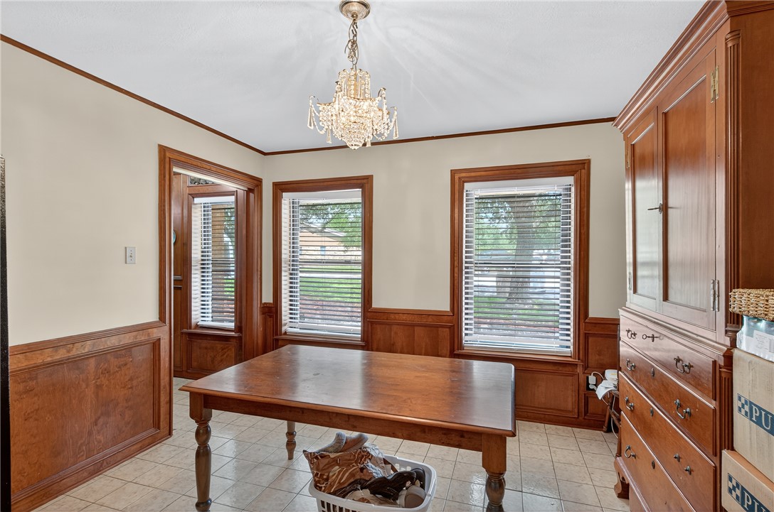 3501 Broad Oak Circle Bryan, TX 77802 - Photo 4 of 28 Dining space with wainscoting, crown molding, wood walls, and a chandelier