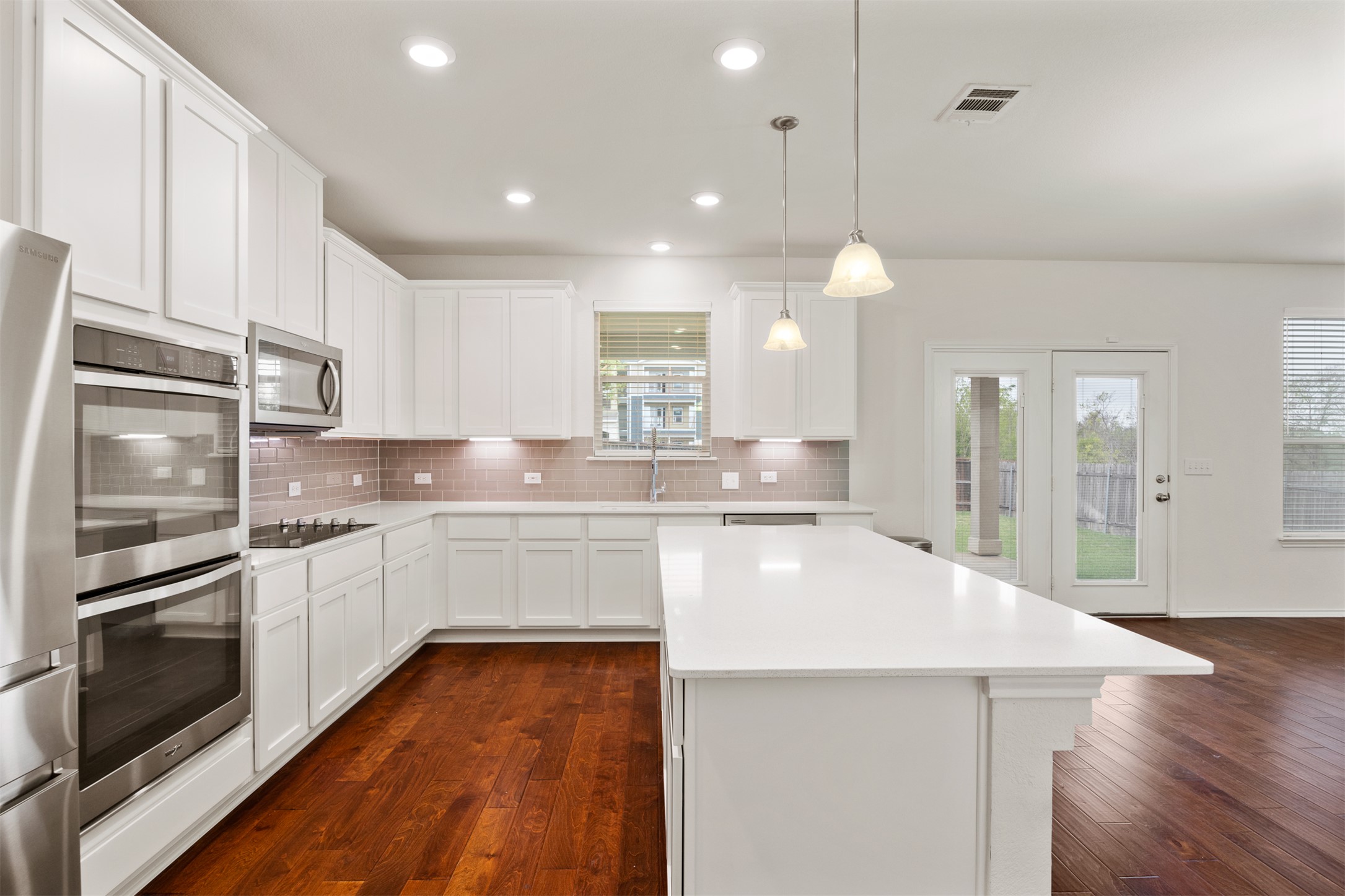 7009 Nutria Run Austin, TX 78744 - Photo 7 of 15 White cabinetry and rich wood floors define this light-filled kitchen, perfect for culinary adventures.