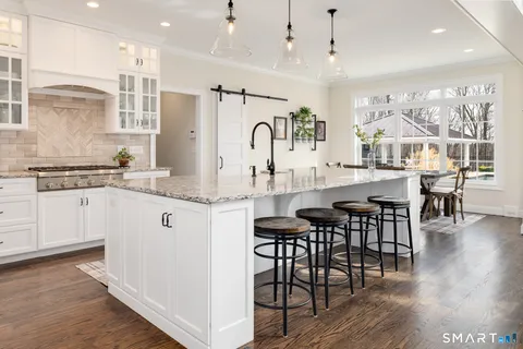 a kitchen with granite countertop a table chairs stove a sink and dishwasher with wooden floor
