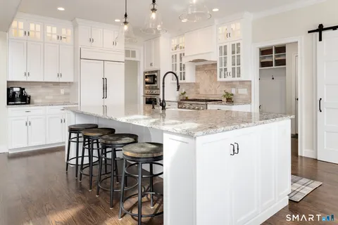 a kitchen with stainless steel appliances granite countertop a stove top oven a sink a refrigerator and white cabinets