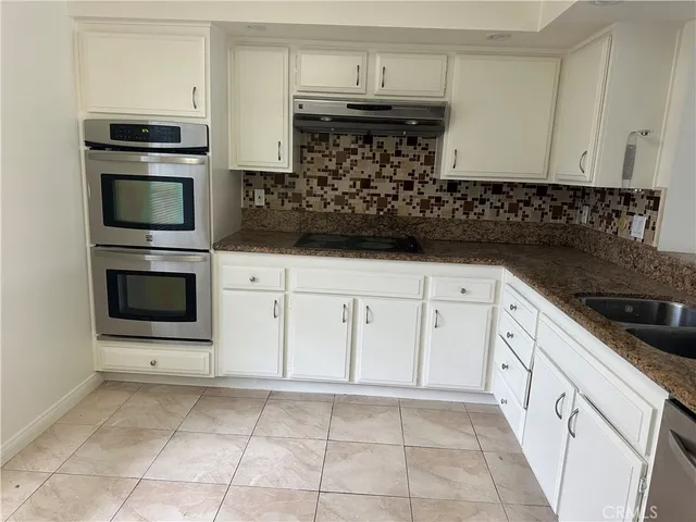 a kitchen with granite countertop white cabinets and stainless steel appliances
