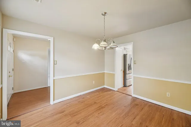 a view of empty room with wooden floor chandelier and window