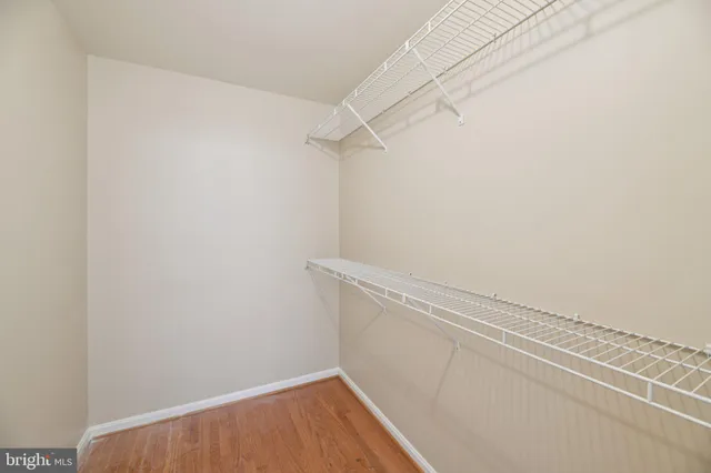 an empty room with wooden floor window and ceiling fan