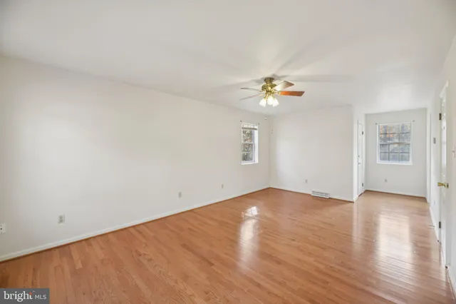 an empty room with windows and fan