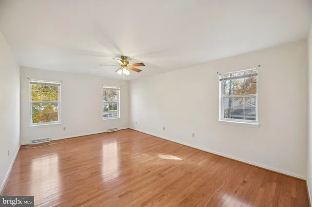 an empty room with a window and chandelier fan