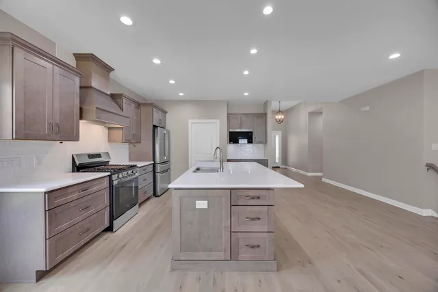 a kitchen with stainless steel appliances granite countertop a sink stove and refrigerator