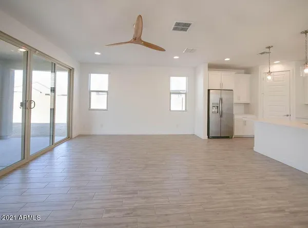 an empty room with wooden floor and a kitchen