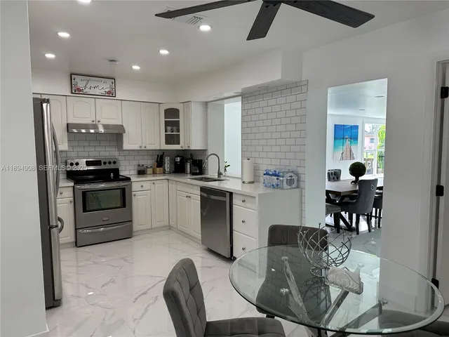 a kitchen with stainless steel appliances kitchen island granite countertop a stove a sink a microwave a dining table and chairs
