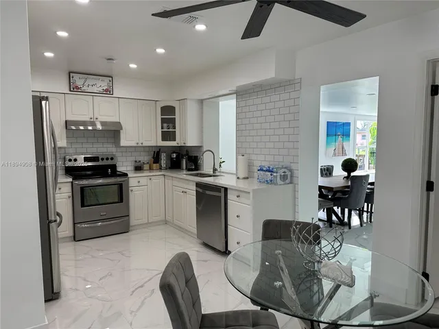 a kitchen with stainless steel appliances kitchen island granite countertop a stove a sink a microwave a dining table and chairs